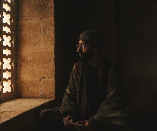 Person meditating peacefully near a window with soft light.